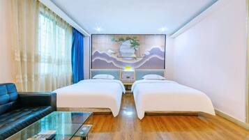 A hotel room with two beds, a sofa, a glass coffee table, and a wall-mounted artwork.