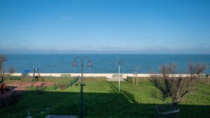 A park with a bench, swings, and a view of the sea.
