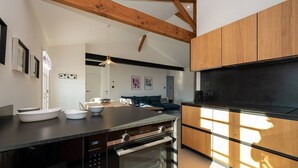 A modern kitchen with a central island, built-in oven, and wooden cabinets.