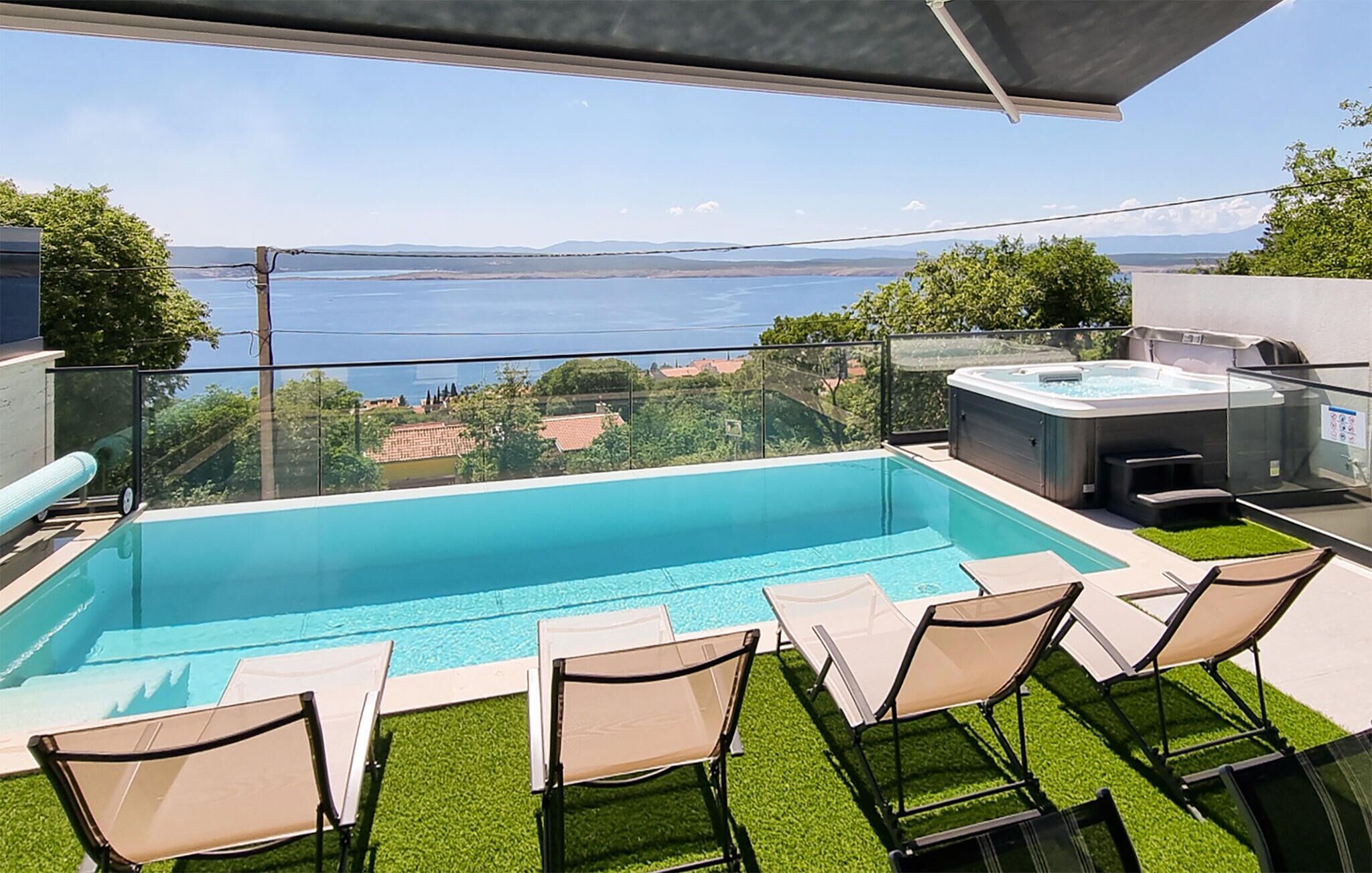 Una piscina en la azotea con vista al mar, rodeada de sillones de descanso y un jacuzzi.