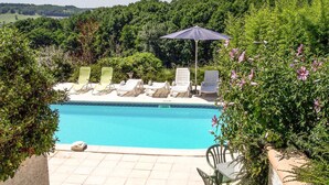 Ein Schwimmbecken mit Liegestühlen und einem Sonnenschirm.
