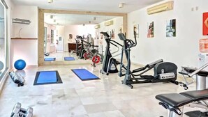 A gym with exercise equipment, blue mats, and dumbbells.
