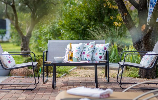 A patio with a table set for two, featuring a bottle of champagne, a bowl, and a glass.