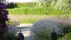 A garden pathway leading to a gazebo with two lanterns, surrounded by lush greenery and flowering plants. - Small charming villa (Tamesluht)
