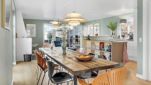 A modern kitchen with a wooden dining table, chairs, pendant lights, and a built-in island with a sink and storage. - 4 bedroom lovely home in Vejby (Vejby)