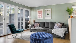 A living room with a grey sofa, a blue ottoman, a teal chair, and a white lamp. There are two framed pictures on the wall. - 4 bedroom lovely home in Vejby (Vejby)