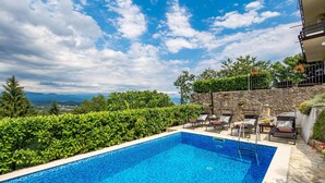 A clear blue pool with lounge chairs and a stone wall. - 2 bedroom amazing apartment in Matulji (Matulji)