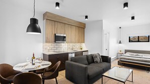 Ein modernes, kompaktes Wohnzimmer mit Küchenzeile, Essbereich und Schlafzimmer.