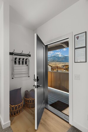 A room with a door leading to a balcony with a mountain view. There are two wicker baskets and a grey door.
