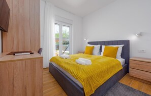 Ein modernes Schlafzimmer mit einem großen Bett, einem Holztisch und Blick ins Freie.