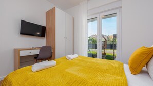 A hotel room with a bed, a desk, a chair, a TV, and a view of the outside. - Awesome apartment in Zadar with WiFi (Zadar)