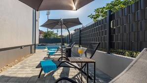 A sunlit outdoor seating area with lounge chairs and tables, a pool, and a high fence. - Awesome apartment in Zadar with WiFi (Zadar)