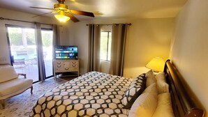 A hotel room with a bed, a chair, a TV, and a ceiling fan.