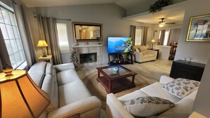 A living room with a sofa, armchair, coffee table, and a television.