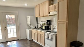 Une cuisine avec des meubles de rangement en bois, un réfrigérateur blanc, une cuisinière et un évier.