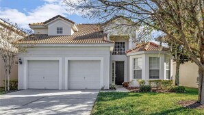 A two-story house with a garage, a covered porch, and a well-maintained lawn.