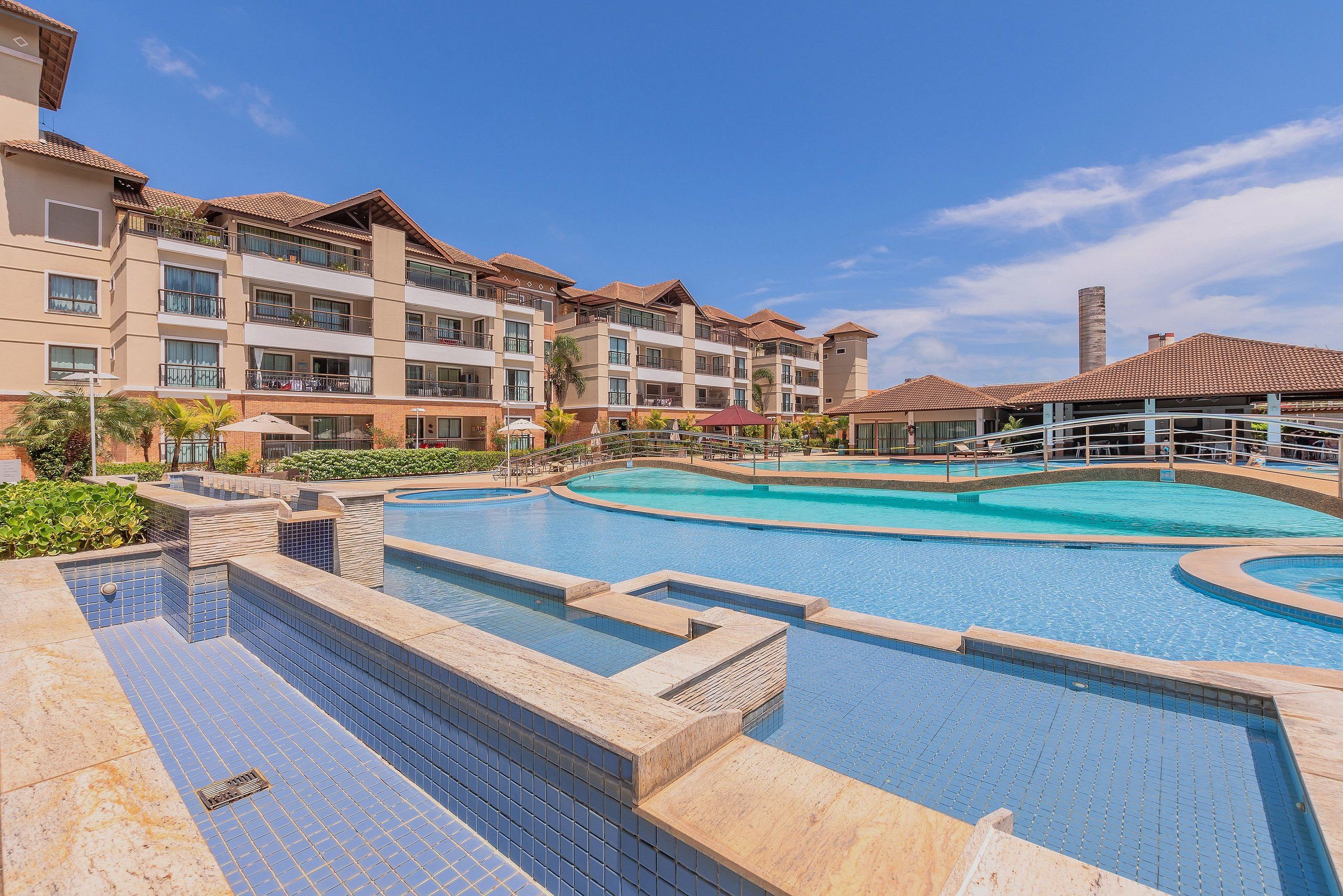 Un hotel con varios balcones, piscina y un puente cubierto.