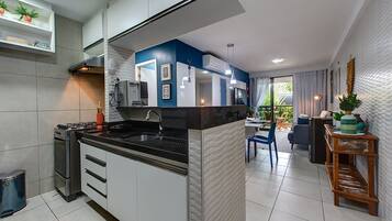 Cozinha moderna com ilha central, área de jantar com mesa e cadeiras, e vista para o exterior.