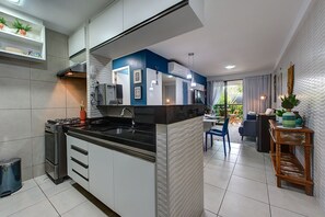 A modern kitchen with a central island, a dining area with a table and chairs, and a view of the outdoors.