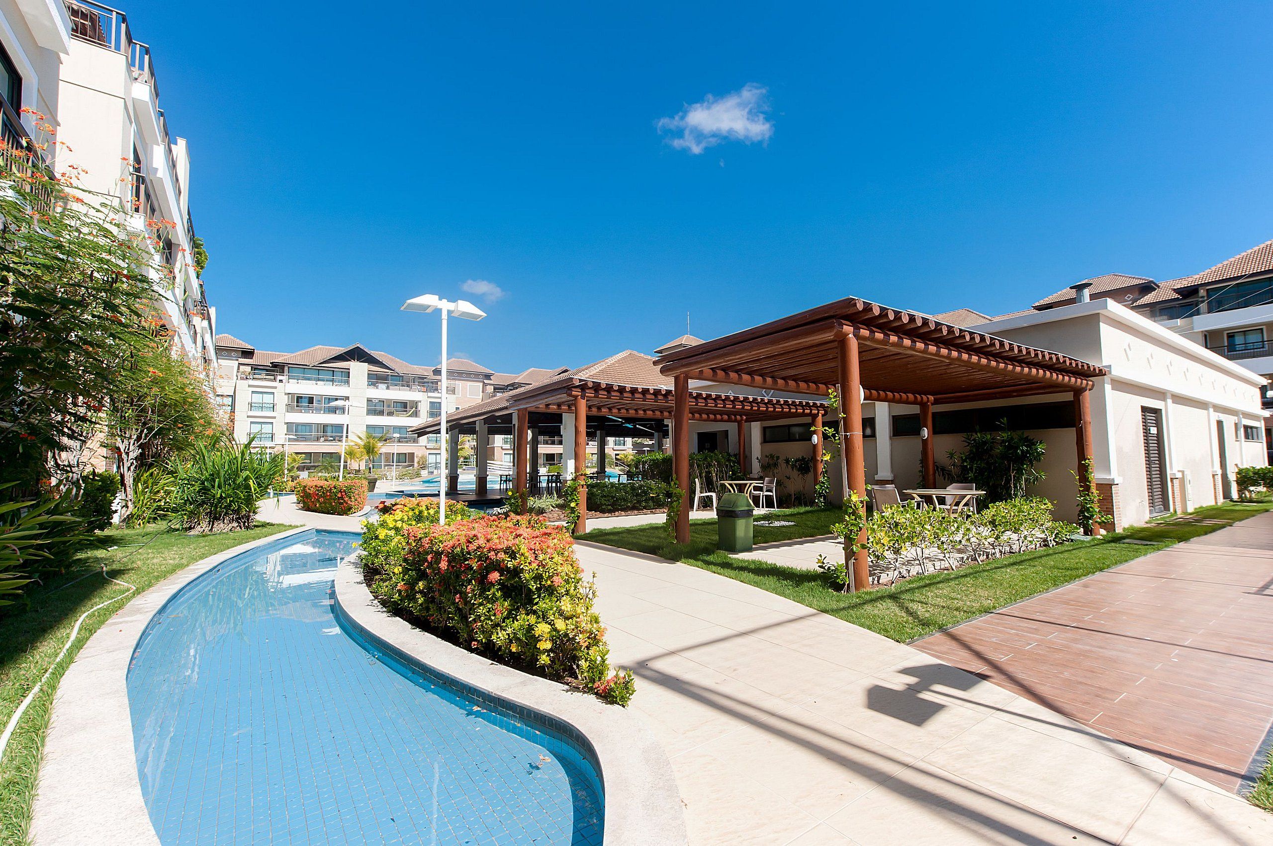 Edifício residencial com piscina, área de estar ao ar livre e céu azul límpido.