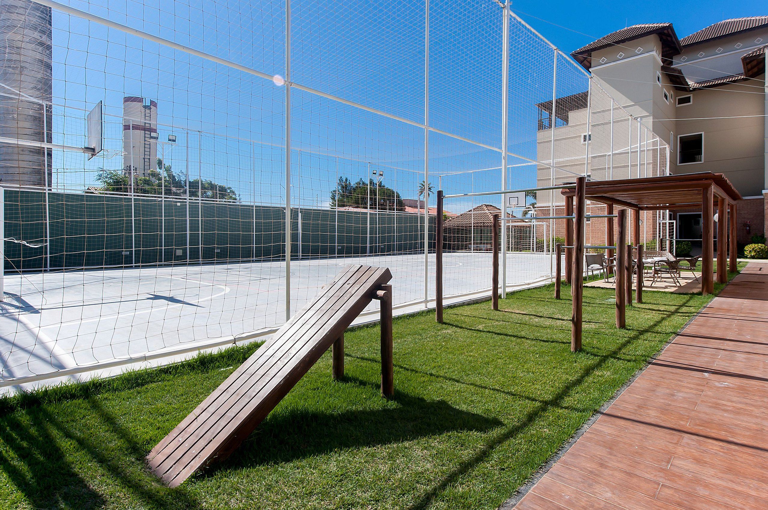 Una cancha deportiva con un banco de madera y una estructura de pérgola.