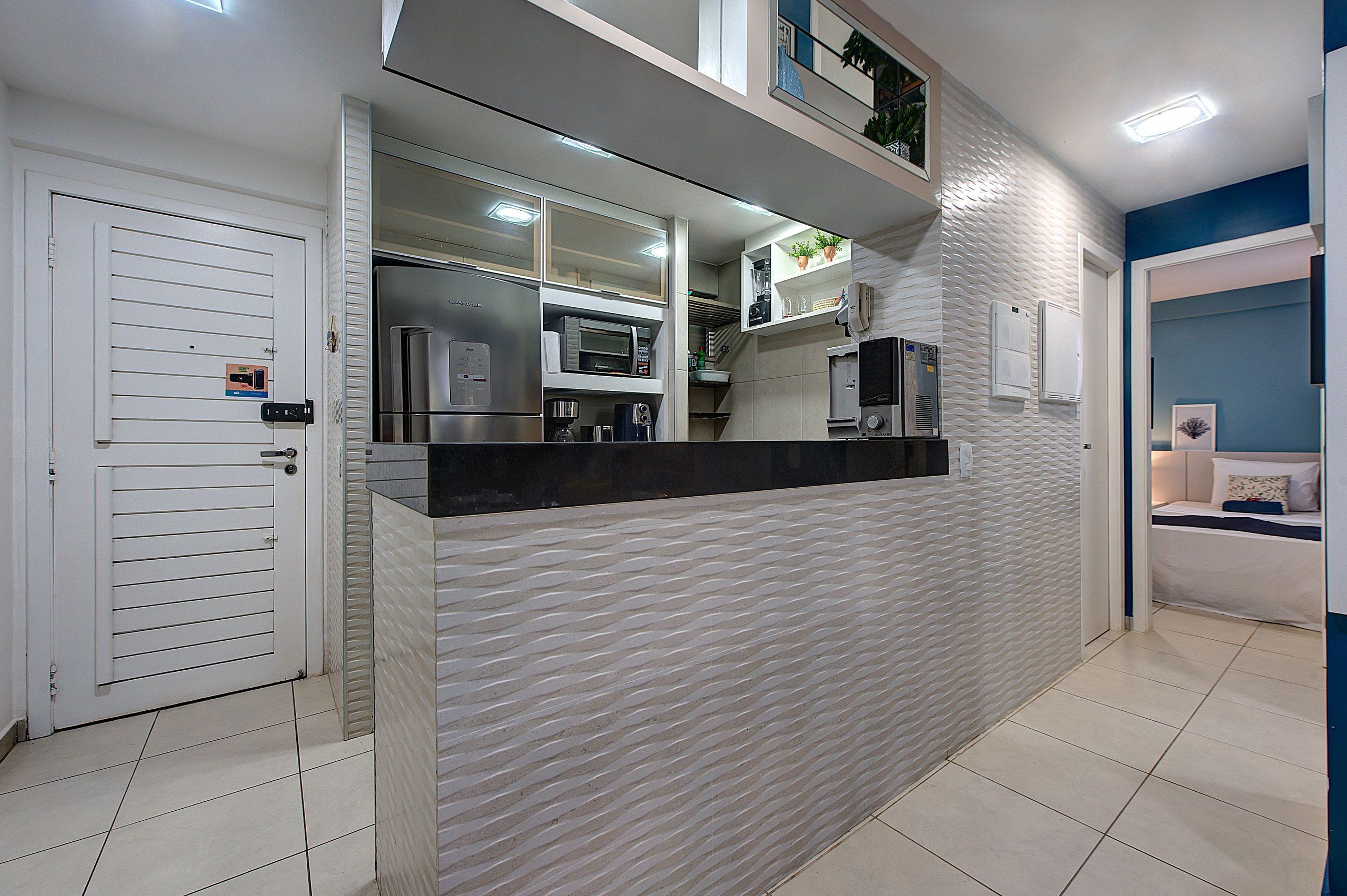 Cozinha compacta com micro-ondas, cafeteira e geladeira.