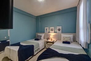 Een hotelkamer met twee bedden, een flatscreen televisie en een nachtkastje met een lamp.