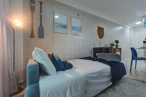 Quarto com cama, almofadas, escrivaninha, cadeira e decorações nas paredes.