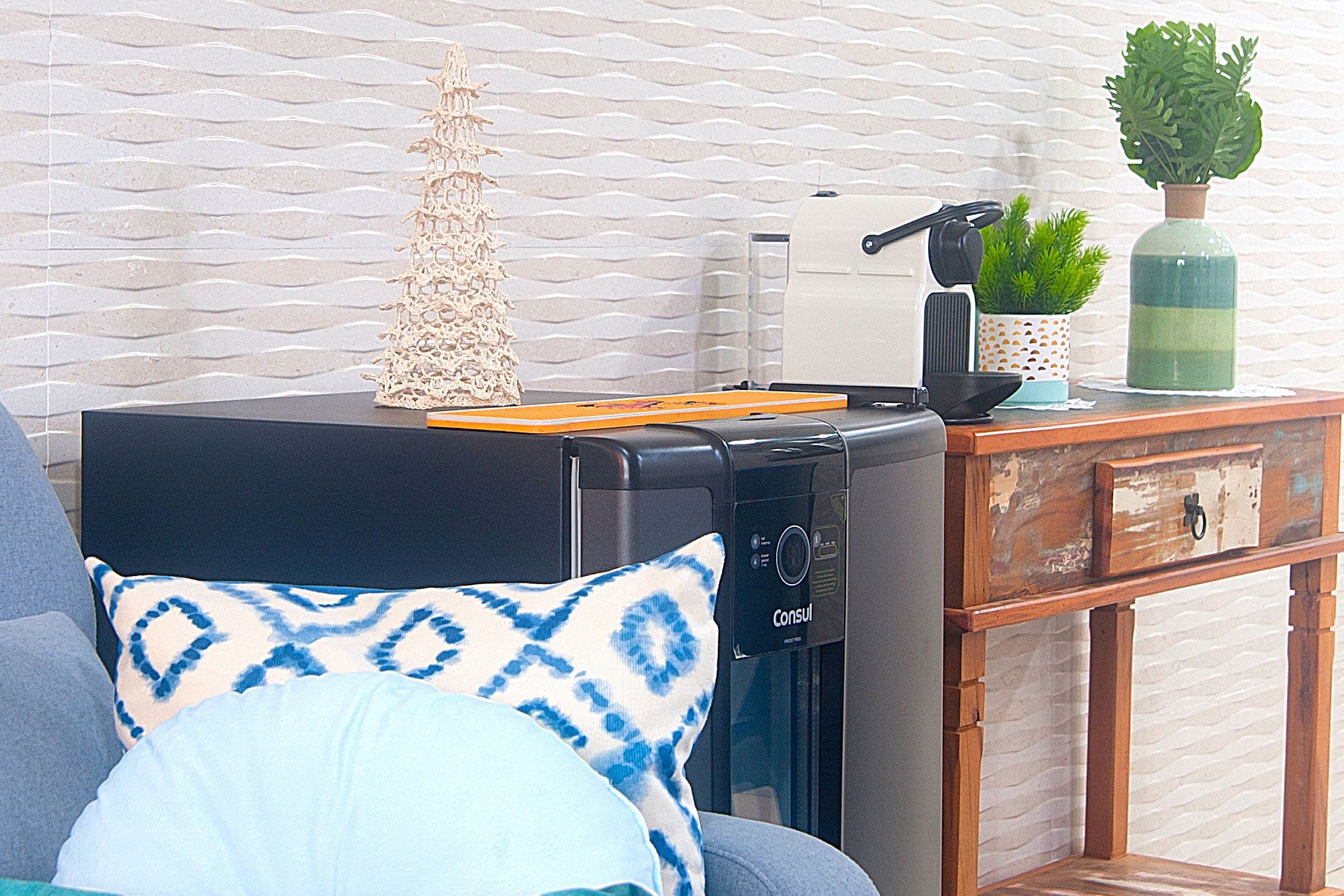 Uma cozinha compacta com cafeteira, uma pequena planta e um enfeite de árvore em uma bancada.