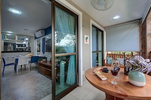 A modern kitchen with a dining area, a balcony with a view, and a table set for dining. - Apart em Porto das Dunas por Carpediem (Aquiraz)