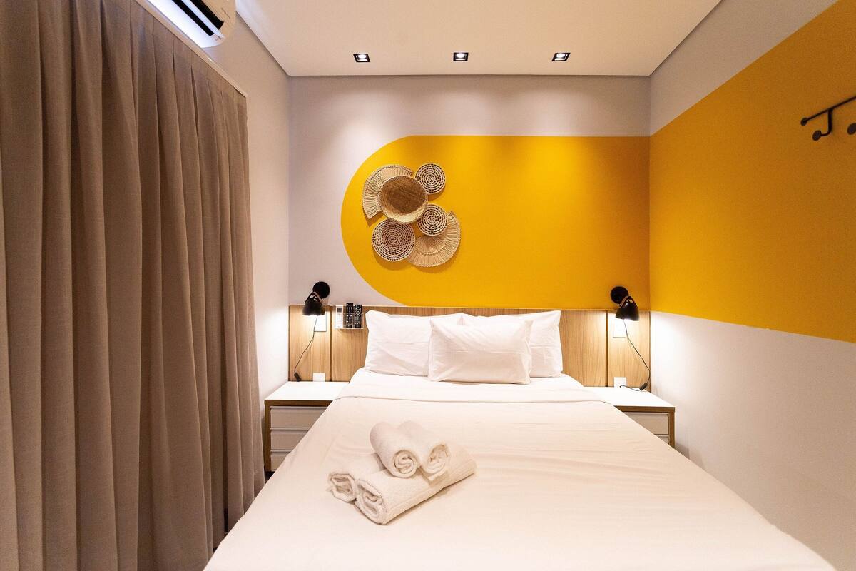 Une chambre d’hôtel avec un lit, une table de chevet, une lampe et un élément décoratif mural.