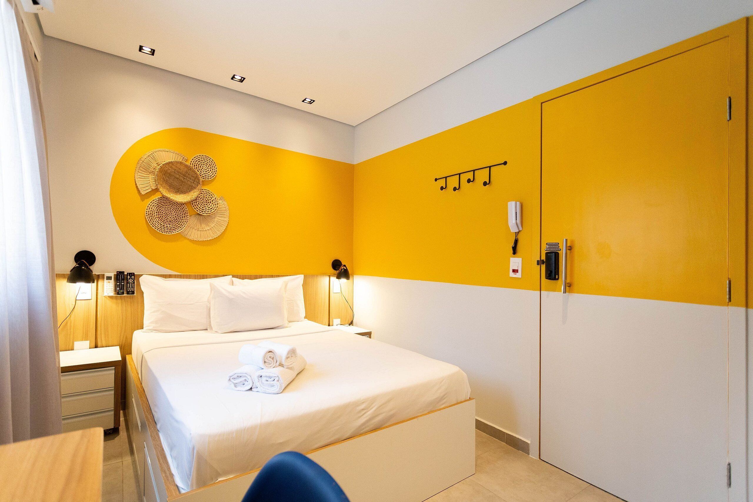 A hotel room with a bed, bedside tables, a wardrobe, and a wall decoration.