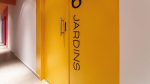 Un pasillo con una pared amarilla y una puerta con la inscripción '6 JARDINS'.