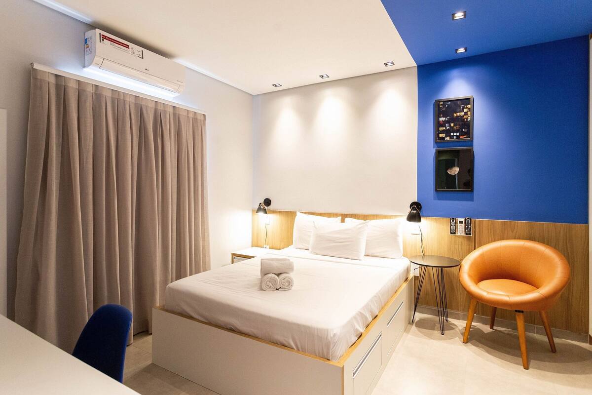 Une chambre d’hôtel moderne équipée d’un lit, d’un bureau, d’une chaise et d’une petite table.
