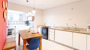 Una cocina moderna con armarios blancos, una mesa de comedor de madera e iluminación colgante.