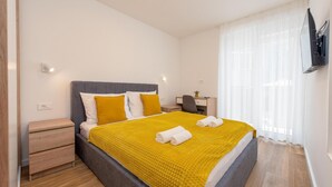 Een moderne hotelkamer met een groot bed, een bureau en een aan de muur bevestigde televisie.
