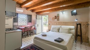 Une chambre avec un lit, un bureau et une chaise. Il y a un téléviseur accroché au mur et une fenêtre donnant sur l’extérieur.