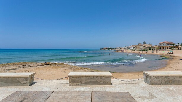 Une plage offrant une vue dégagée sur la mer, une rive sablonneuse et des bâtiments en arrière-plan.