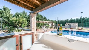 Un espace extérieur avec une piscine, une pergola, des chaises longues et une bouteille de vin.