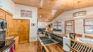 Una cucina con mobili in legno, un piano cottura nero e un'area pranzo con un tavolo e sedie di legno.