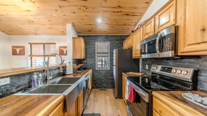 Una cucina moderna con mobili in legno, elettrodomestici in acciaio inossidabile e una parete rivestita in pietra.