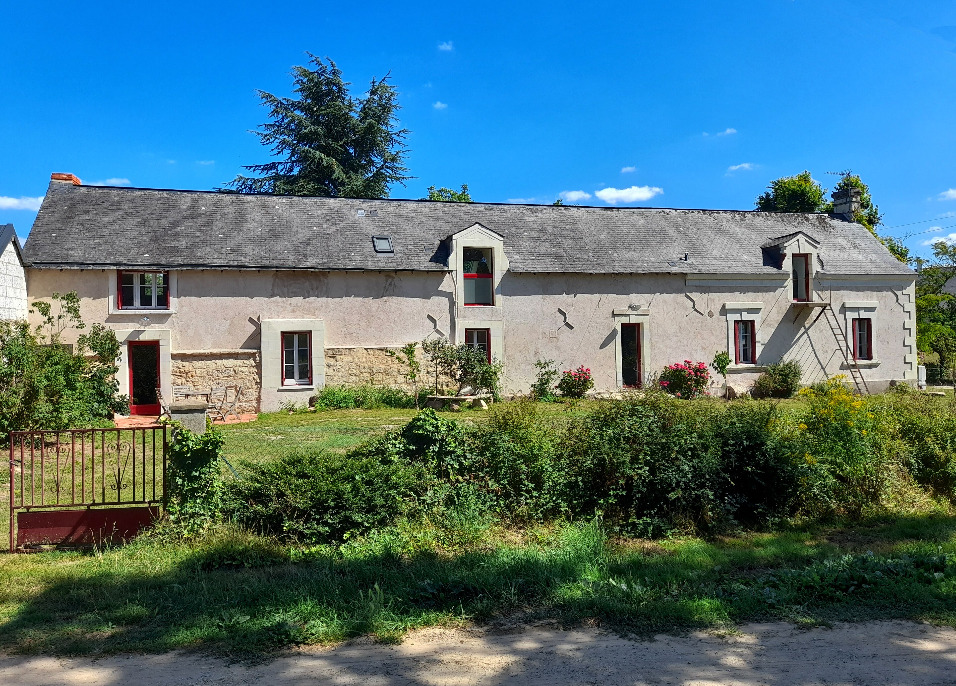 A two-story house with a stone foundation, multiple windows, and a red door.