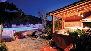 A stone pool with lounge chairs, a wooden pergola, and a kitchen area with a tiled backsplash. - Beach front home in Vinisce with sauna (Vinisce)