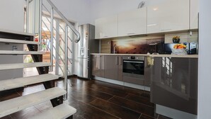 A modern kitchen with stainless steel appliances, a wooden floor, and a view of the outdoors through a glass door. - Beach front home in Vinisce with sauna (Vinisce)