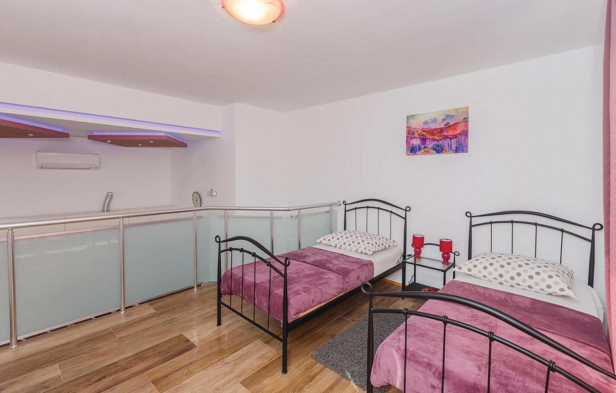 Ein Schlafzimmer mit zwei Betten, einer kleinen Küchenzeile und einem Bild an der Wand.