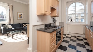 A modern kitchen with wooden cabinets, a black countertop, and a checkered floor. - Fantastic corner 2 bedroom property with astounding views of the famous historic Royal Mile. (Edinburgh)