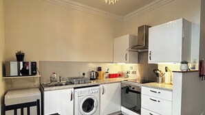 A compact kitchen with a washing machine, oven, and microwave. - Economical 2 bedroom property just off the famous Royal Mile (Edinburgh)