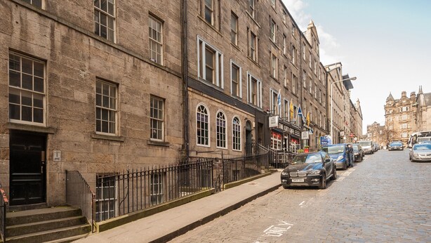 A historic stone building with multiple windows and a black metal fence. - Economical 2 bedroom property just off the famous Royal Mile (Edinburgh)