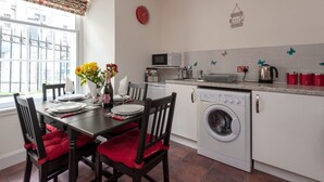 A compact kitchen with a dining area, a washing machine, and a microwave. - Economical 2 bedroom property just off the famous Royal Mile (Edinburgh)