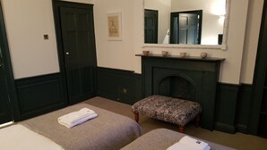 A hotel room with two beds, a fireplace, a mirror, and a small bench. - fantastic 2 bedroom on a bohemian street in Edinburgh's New Town (Edinburgh)